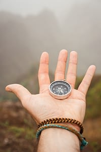 Hand with compass in the misty mountain terrain